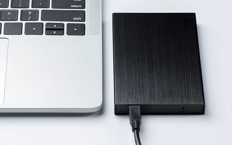 Dizüstü bilgisayara USB kablosuyla bağlı siyah harici hard disk