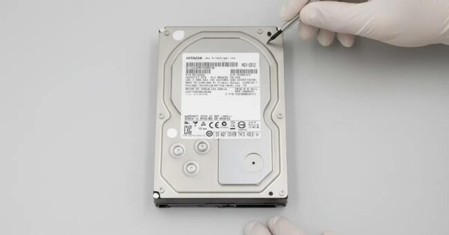 Laboratuvarda eldivenli teknisyen tarafından incelenen 3.5 inç Hitachi sabit disk