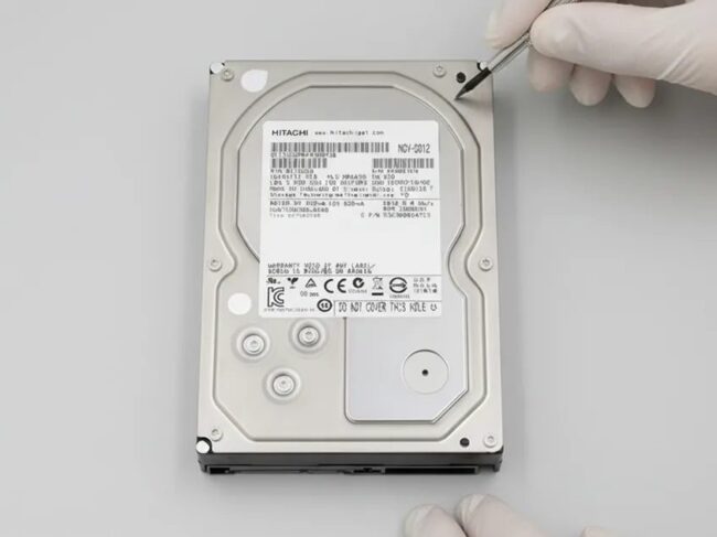 Laboratuvarda eldivenli teknisyen tarafından incelenen 3.5 inç Hitachi sabit disk
