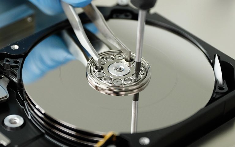 Temiz oda ortamında eldivenli uzmanın açık hard disk plakaları üzerinde çalışması