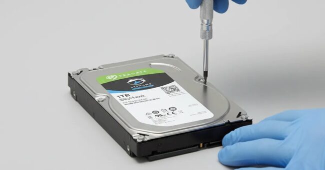 Teknisyenin tornavidayla Seagate SkyHawk 1TB hard diski açmaya hazırlanması